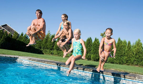 family jumping in pool